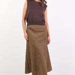 Woman wearing a sleeveless brown top and patterned skirt on a white background