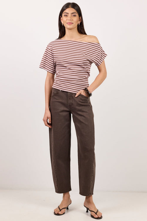 A woman modeling a short-sleeve off-the-shoulder top with thin red and white horizontal stripes, paired with dark brown cropped pants and black thong sandals, against a plain white studio background.