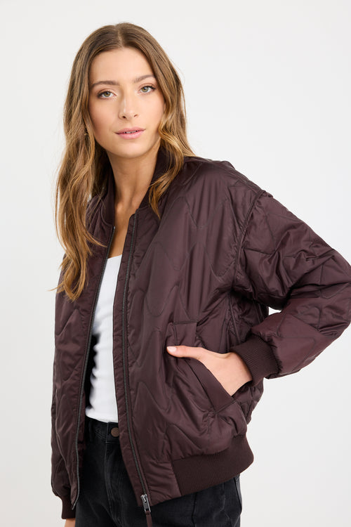 Woman wearing a brown quilted jacket on a white background