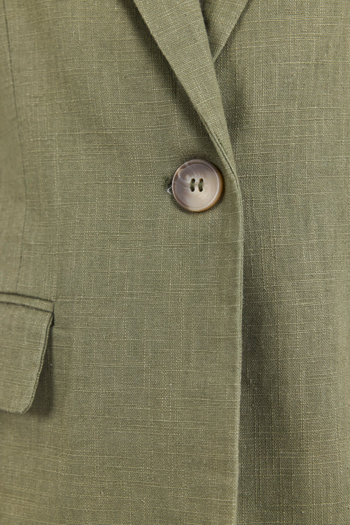 Close-up of a green blazer with a button on a matching fabric background