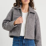 Woman wearing a gray jacket, white shirt, and blue jeans on a white background