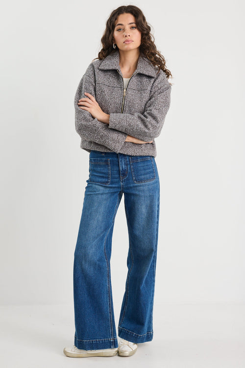 Woman wearing a gray sweater and blue jeans on a white background