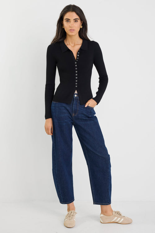 Woman wearing a black cardigan and blue jeans on a white background