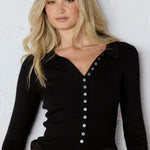 Woman wearing a black button-up shirt with a white background
