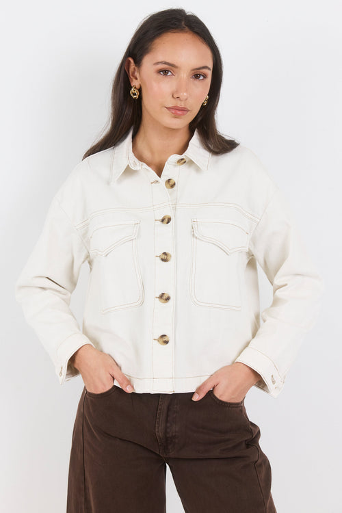 Woman wearing a white denim jacket on a white background