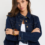 Long sleeve indigo denim jacket with patch pockets, buttoned front, and relaxed fit on model.