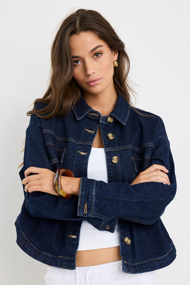 Long sleeve indigo denim jacket with patch pockets, buttoned front, and relaxed fit on model.