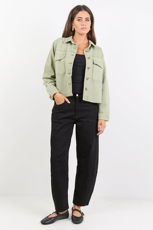 Woman wearing a light green jacket and black pants on a white background