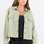 Woman wearing a light green denim jacket on a white background