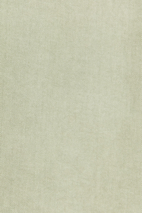 Close-up of a light green denim jacket with stitching details.