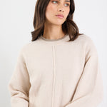 Woman wearing a beige sweater against a white background