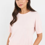 Woman wearing a light pink t-shirt against a white background