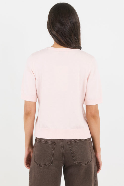 Person wearing a light pink t-shirt and brown pants on a white background
