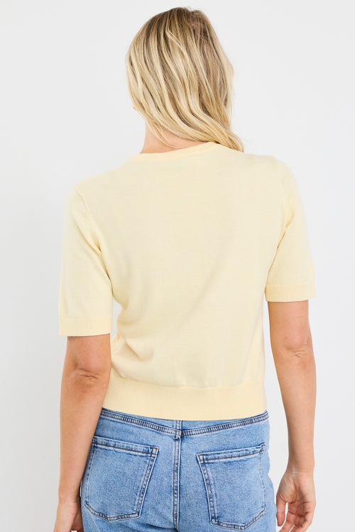 model wears a yellow knit tee with light blue jeans