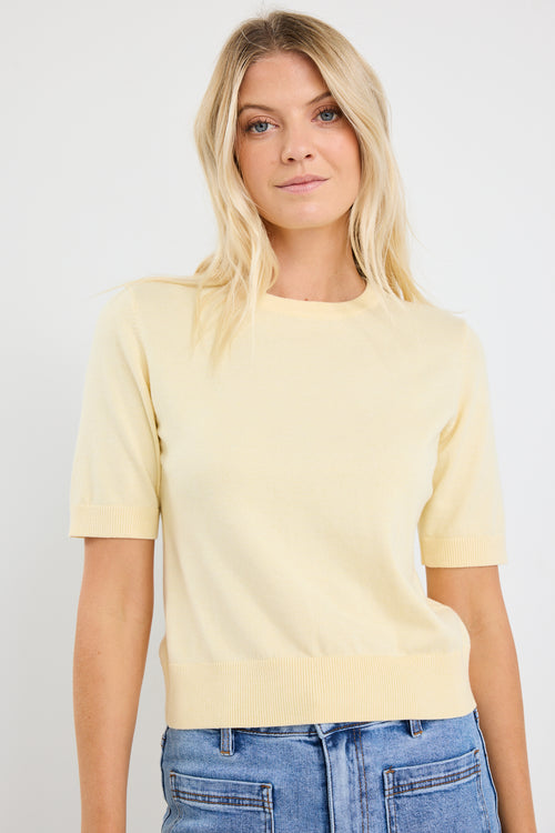 model wears a yellow knit tee with light blue jeans