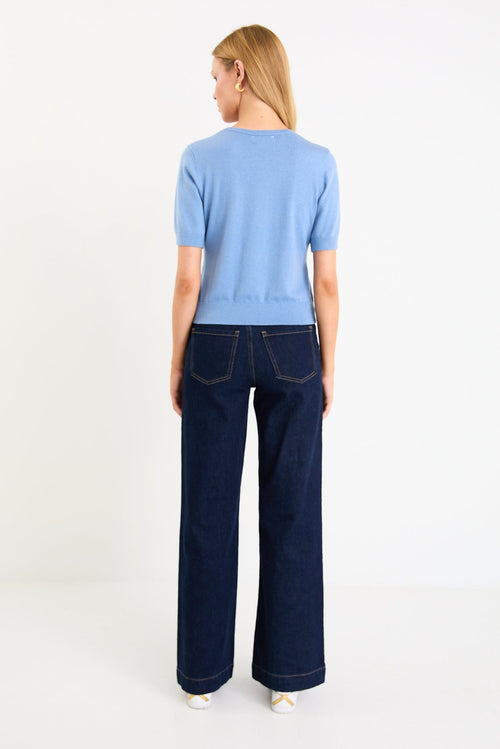 Model wearing a sky blue short sleeve crewneck knit tee tucked into dark denim