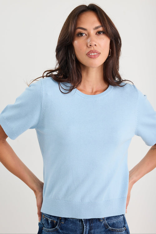 Woman wearing a light blue t-shirt against a plain background