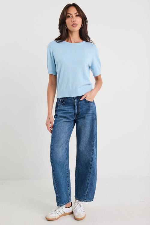 Woman wearing a light blue t-shirt and blue jeans on a white background