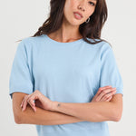 Woman wearing a light blue t-shirt and jeans against a white background