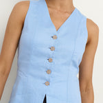model wears a light blue linen vest with dark blue wide leg jeans