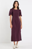 Woman wearing a purple dress with puffed sleeves on a white background