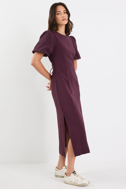 Woman wearing a purple dress with puffed sleeves on a white background