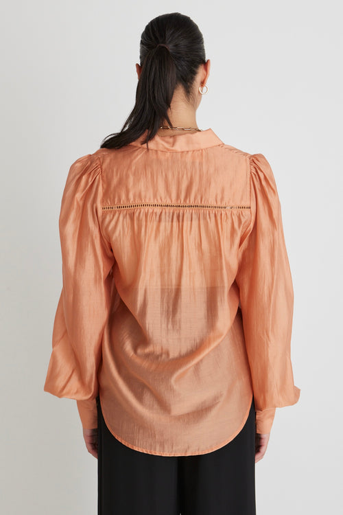 model wears a orange blouse