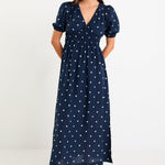 Model wearing a navy polka dot maxi dress with a V neckline, flutter sleeves and an elasticated waist