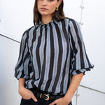 Woman wearing a black and gray striped blouse with a white background