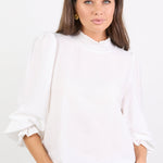 Woman wearing a white blouse and blue jeans against a white background