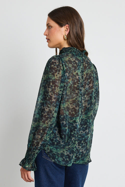 A woman wearing an ivory quarter-zip jumper with ribbed and cable-knit detailing, styled with blue denim jeans.