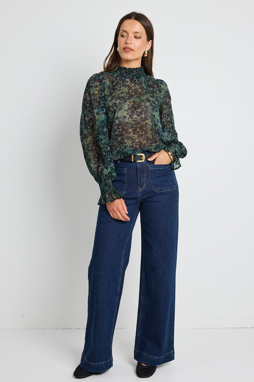 A woman wearing an ivory quarter-zip jumper with ribbed and cable-knit detailing, styled with blue denim jeans.