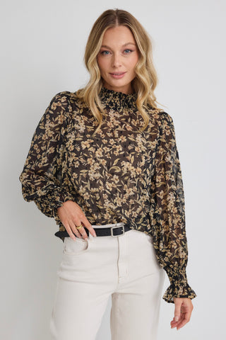 model wears a black and gold floral top