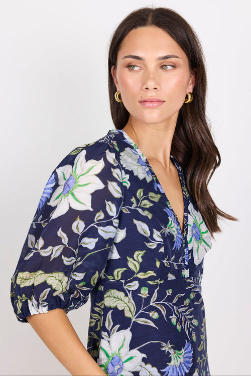 Woman wearing a navy floral dress against a white background