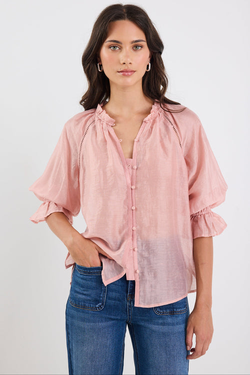 Woman wearing a pink blouse and blue jeans on a white background