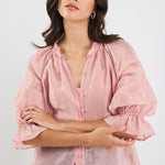 Woman wearing a pink blouse with ruffled sleeves on a white background