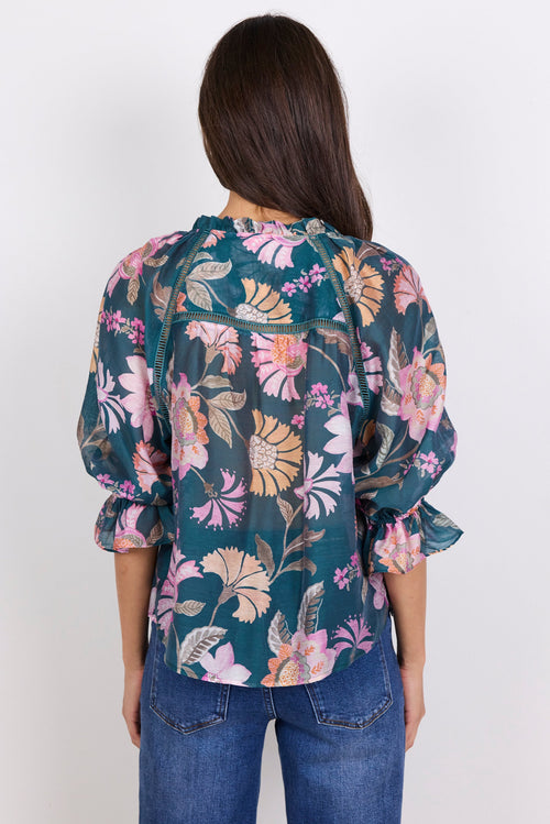 Woman wearing a floral blouse with rolled-up sleeves on a white background
col_pattern