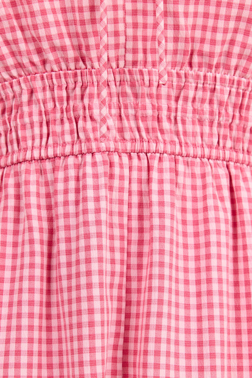 Close-up of a pink and white gingham check fabric with a smocked elastic waistband.