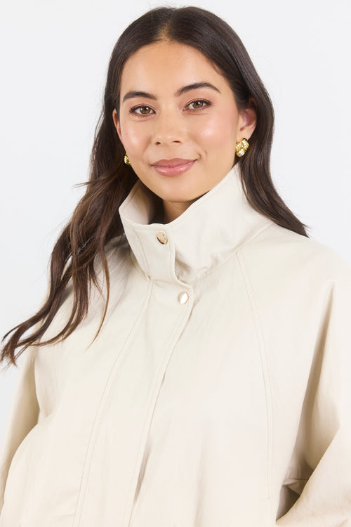 Woman wearing a cream-colored coat against a white background
