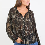Woman wearing a patterned blouse and blue jeans on a white background