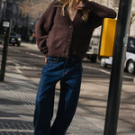Woman leaning against a street lamp on a city street