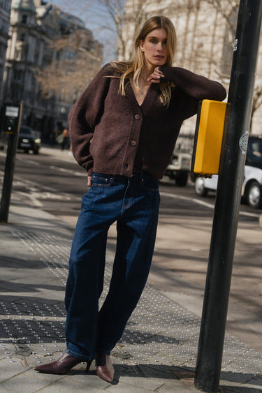 Woman leaning against a street lamp on a city street