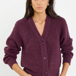 Woman wearing a purple cardigan and blue jeans on a white background