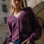 Woman wearing a purple cardigan in front of an 'Underground' sign.