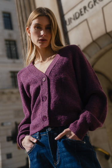 Woman wearing a purple cardigan in front of an 'Underground' sign.