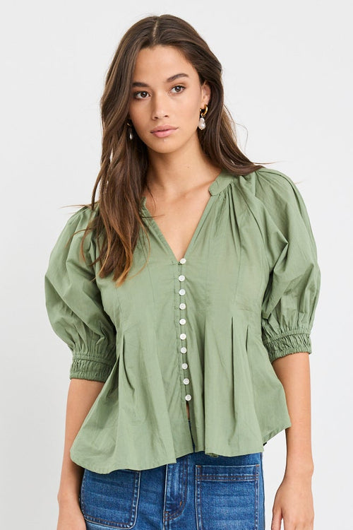 Woman wearing a green blouse and blue jeans on a white background