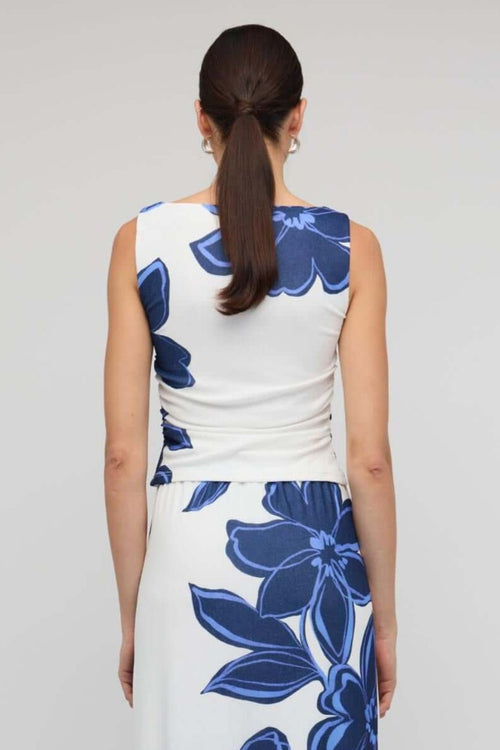 Woman wearing a white sleeveless mesh top with bold blue floral print, styled with blue denim jeans for a casual yet polished look.