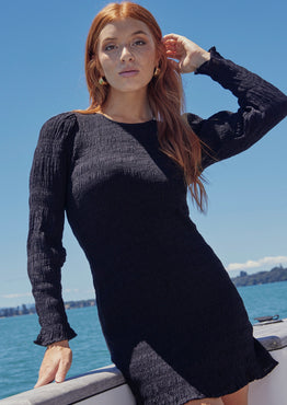 model wears a black long sleeve mini dress