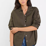 Woman wearing an olive green button-up shirt and blue jeans on a white background