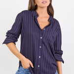Women wearing navy shirt with white stripes and blue jeans on white background.